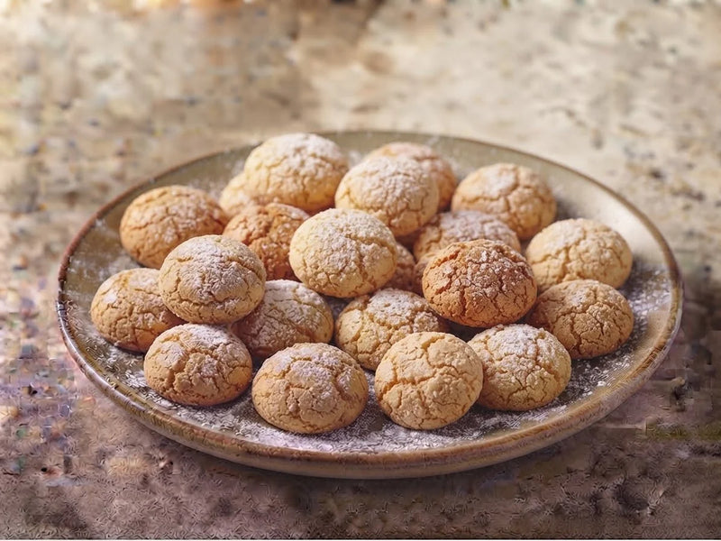 Un piatto di dessert di mandorla, biscotti tondi spolverati di zucchero a velo